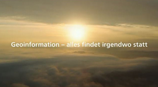 Imagefilm über Geoinformation Der Bildausschnitt aus dem Imagefilm über Geoinformation zeigt die Sonne über den Wolken. Davor der Text: Geoinformation - alles findet irgendwo statt.