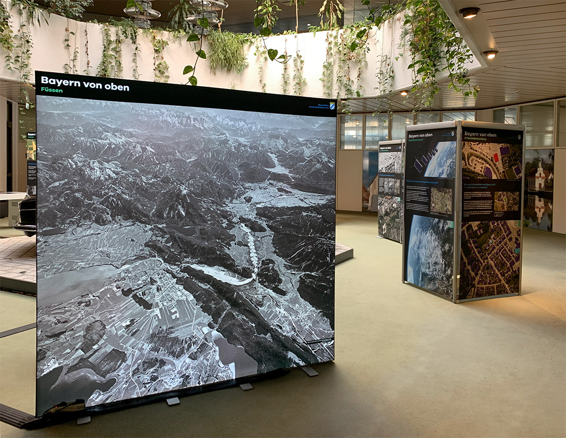 Wanderausstellung "Bayern von oben" in Krumbach Blick in den Ausstellungsraum, im Vordergrund ein großes Schwarz-Weiß-Luftbild von Füssen.